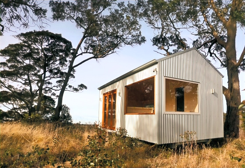 Completed white cabin with corner windows in a grassy landscape
