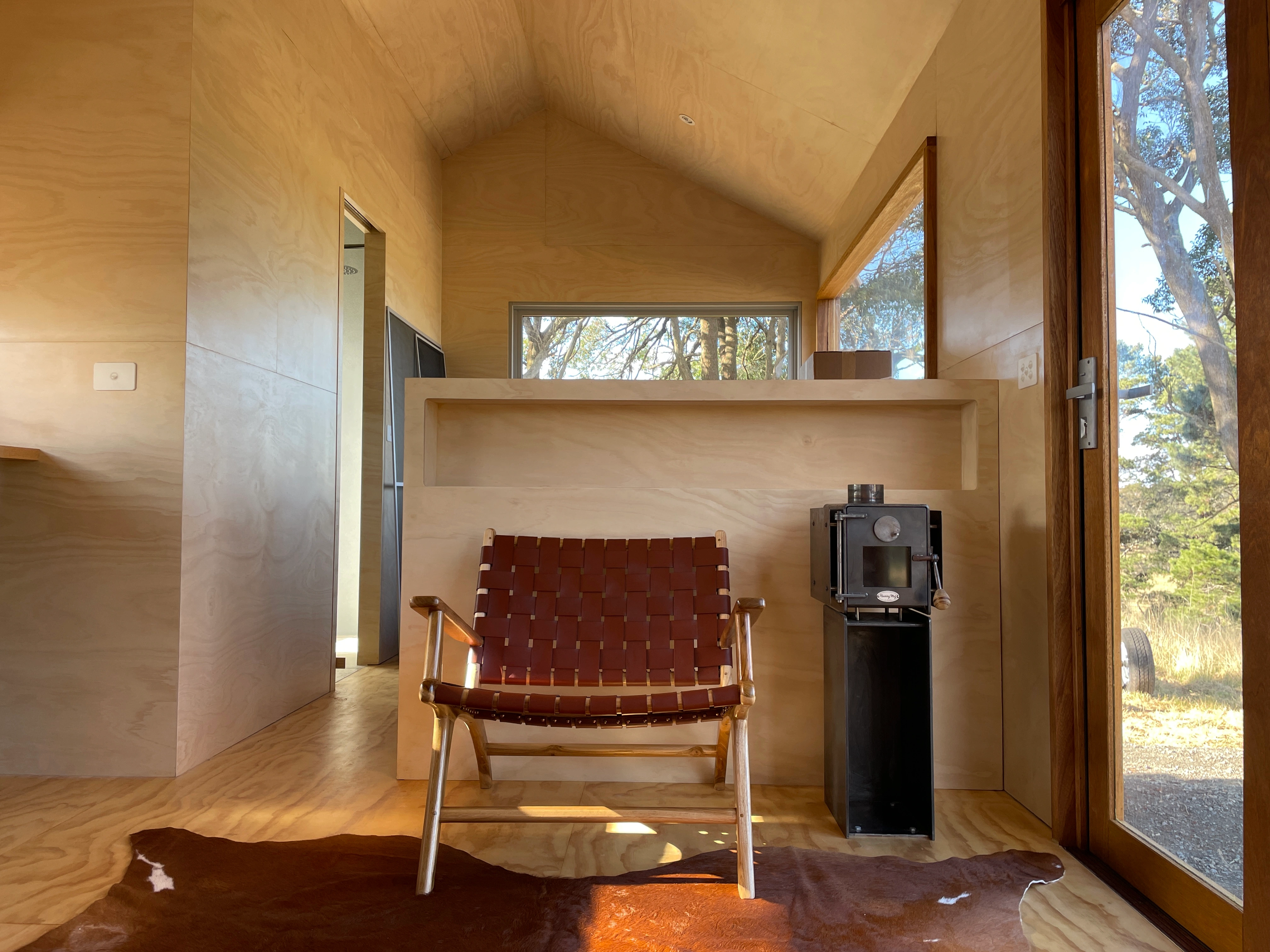 Timber-lined cabin interior with a leather chair and wood-burning stove